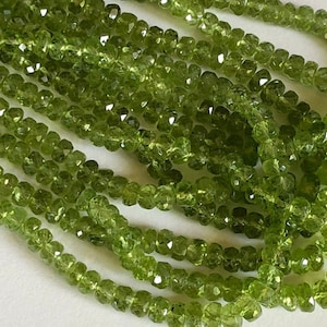 May include: A strand of green peridot beads, faceted and strung on a wire. The beads are small and uniform in size, creating a delicate and elegant look.
