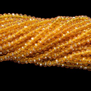 May include: A strand of amber-colored faceted glass beads. The beads are small and round, and they are strung together on a clear thread.