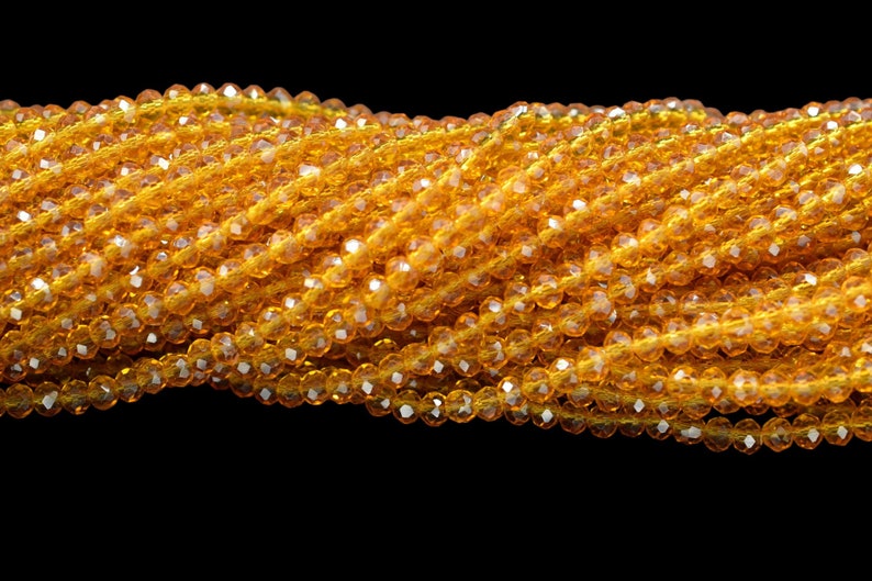 May include: A strand of amber-colored faceted glass beads. The beads are small and round, and they are strung together on a clear thread.