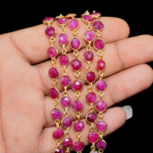 May include: A strand of ruby gemstone beads strung on a gold chain. The beads are faceted and have a deep red colour.