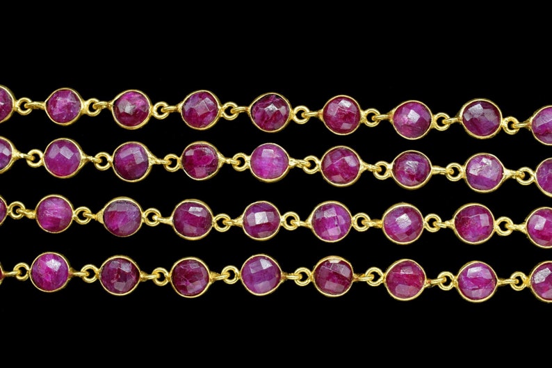 May include: A strand of ruby gemstone beads connected by gold chain links. The beads are faceted and have a deep red colour.