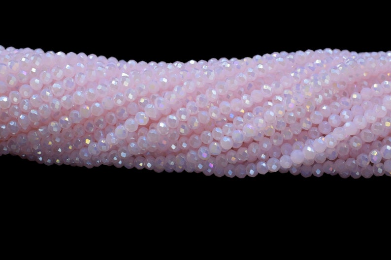 以下が含まれることがあります： ピンクの虹色のガラスビーズのストランド。ビーズはファセットカットされており、わずかに不規則な形をしています。