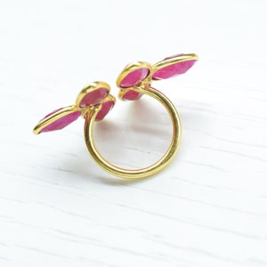 Peut inclure: Une bague en or avec trois accents de pierres pr&eacute;cieuses roses. La bague est ouverte et les pierres pr&eacute;cieuses sont dispos&eacute;es en forme de fleur.