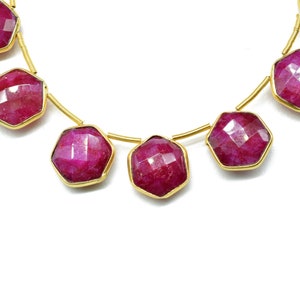 May include: A necklace with a gold chain and faceted ruby gemstones. The ruby stones are set in gold bezels and are connected by gold jump rings.