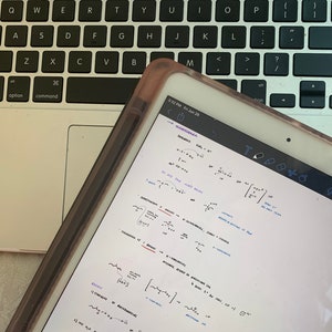 Può includere: Primo piano dello schermo di un tablet digitale che mostra equazioni e formule matematiche scritte a mano. Il tablet è appoggiato sulla tastiera di un laptop.