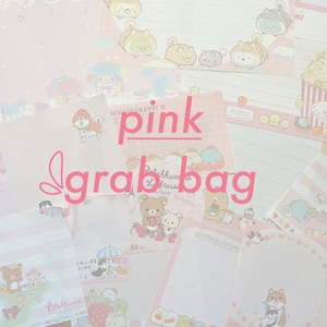 May include: A pink grab bag filled with various stationery items featuring cute cartoon characters. The bag includes letter paper, notepads, and stickers with designs of Hello Kitty, Rilakkuma, and other popular Japanese characters.