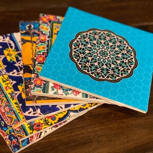 May include: A stack of colorful coasters with intricate geometric patterns. The top coaster features a blue background with a large, ornate, turquoise mandala design.