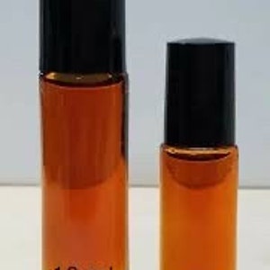 Puede incluir: Dos botellas de vidrio con tapas de rodillo negras llenas de un líquido marrón. La botella más grande está etiquetada como "10 ml" y la botella más pequeña está etiquetada como "1 dram".