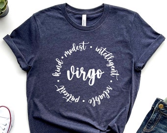 Può includere: Una maglietta blu navy con un design circolare bianco che dice "virgo" al centro e le parole "kind, modest, intelligent, resourceful, patient,  " intorno al cerchio.