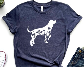 May include: A navy blue t-shirt with a white silhouette of a dog with flowers inside the outline. The dog is standing on all four legs.