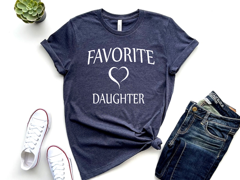 Puede incluir: Una camiseta azul marino con texto blanco que dice "Hija favorita" con un s&iacute;mbolo de coraz&oacute;n blanco.