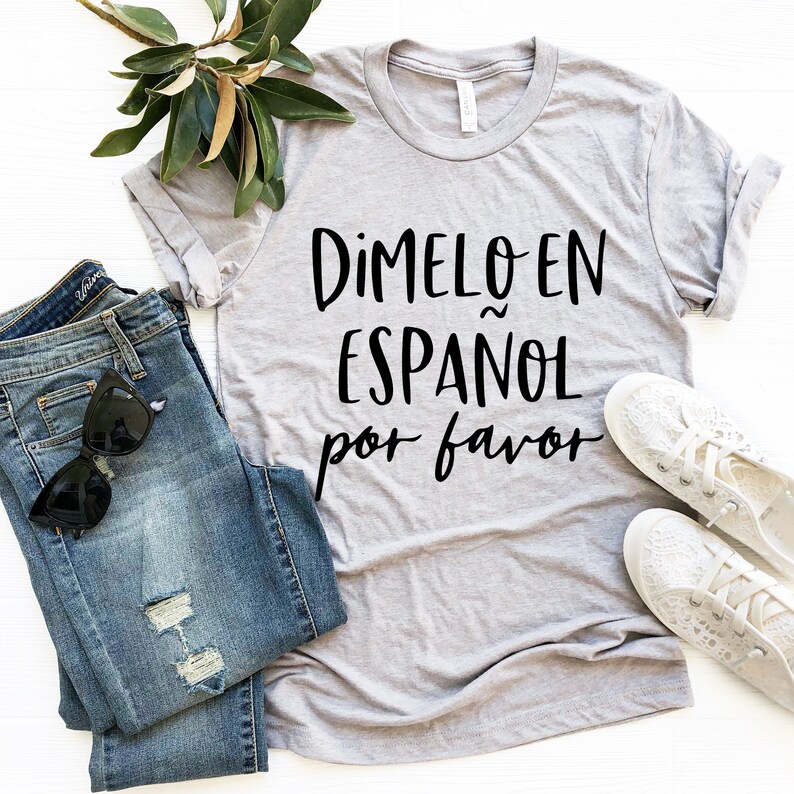 May include: A gray t-shirt with the text "Dimelo en Espa&ntilde;ol por favor" in black lettering.