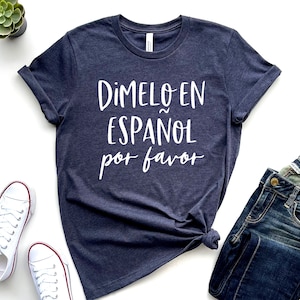 May include: A navy blue t-shirt with white text that reads "Dimelo en Espanol por favor".