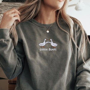 K&ouml;nnte beinhalten: Ein graues Sweatshirt mit einer Grafik von zwei sich k&uuml;ssenden G&auml;nsen und dem Text "Goose Bumps".