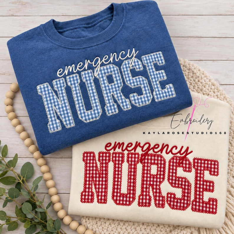 May include: A blue sweatshirt and a cream sweatshirt, each featuring the text "emergency NURSE" embroidered in a gingham pattern. The blue sweatshirt has blue and white gingham lettering, while the cream sweatshirt has red and white gingham lettering.