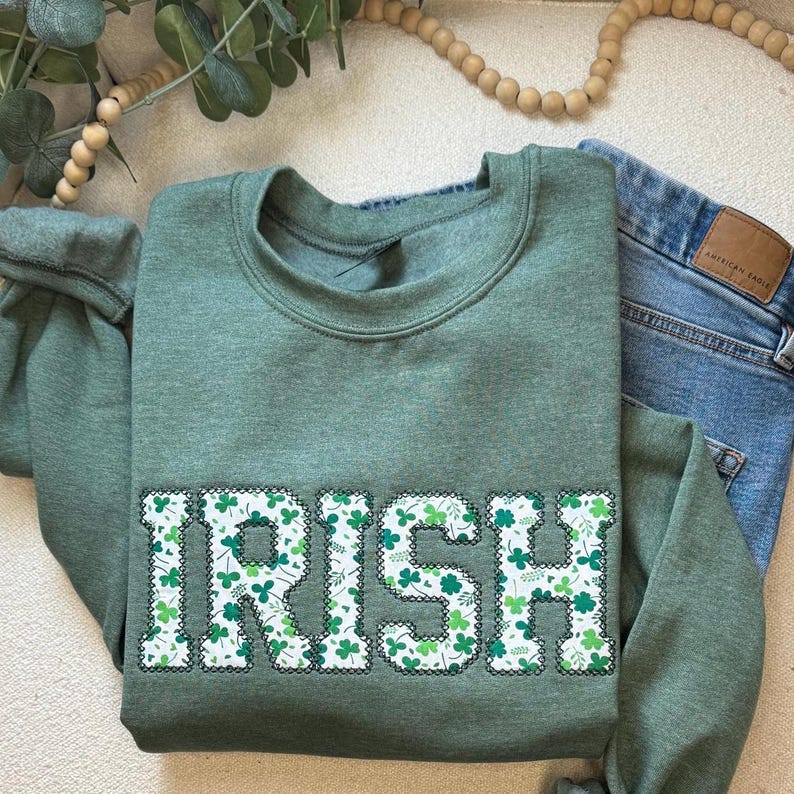 May include: Green sweatshirt with the word "IRISH" in white letters outlined in black. The letters are filled with a pattern of green shamrocks.