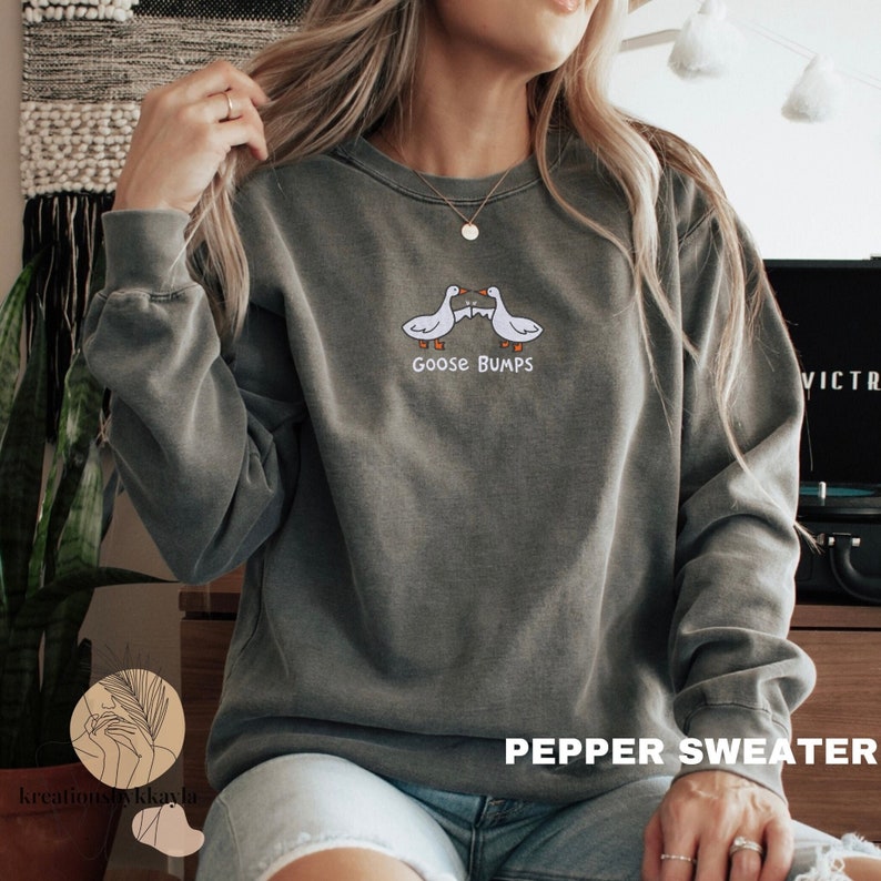 K&ouml;nnte beinhalten: Ein graues Sweatshirt mit einer Grafik von zwei sich k&uuml;ssenden G&auml;nsen und dem Text "Goose Bumps".