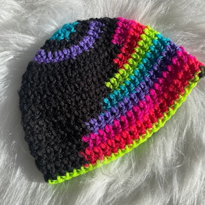 May include: A black crochet beanie with a colorful geometric pattern in shades of pink, purple, green, and blue.