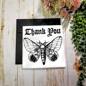 5x5 greeting card featuring a large death moth with a human skull on the back and black shadow of skulls on the bottom wings and the words 'Thank You' in gothic script at the top.