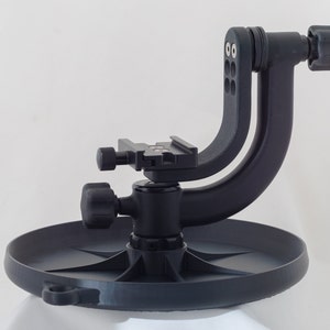 以下が含まれることがあります： 回転ベースとクイックリリースプレートを備えた黒いカメラ三脚。この三脚はマクロ撮影用に設計されており、低角度からの撮影を可能にする湾曲したアームが付いています。