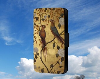 Puede incluir: Una funda de teléfono dorada con un diseño floral y dos pájaros posados en ramas. Los pájaros son marrones y verdes con colas largas.