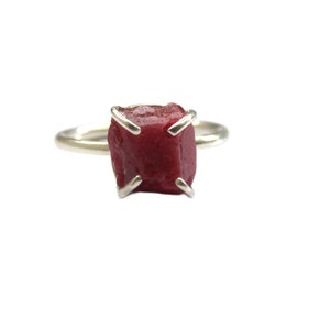 Puede incluir: Un anillo de plata con una piedra preciosa de rubí rojo engastada en garras.