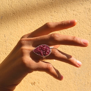May include: A teardrop-shaped ring with a silver setting and a deep red ruby stone.