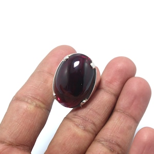 Peut inclure: Une bague en argent avec une grande pierre précieuse rouge foncé de forme ovale.