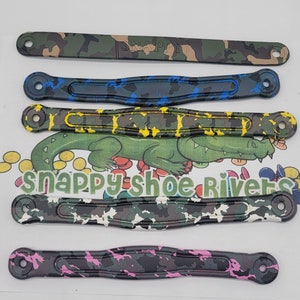 May include: Five different patterned shoe rivets, each with a hole in the center. The rivets are in a variety of camouflage patterns, including green, blue, yellow, white, and pink.