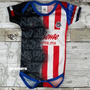 May include: A white, red, and black baby onesie with a team logo and the words "Chivas" and "Chivas.mx".