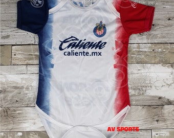 May include: White baby onesie with a red, white, and blue color gradient. The onesie has a team logo and the text "Caliente caliente.mx" printed on the front.