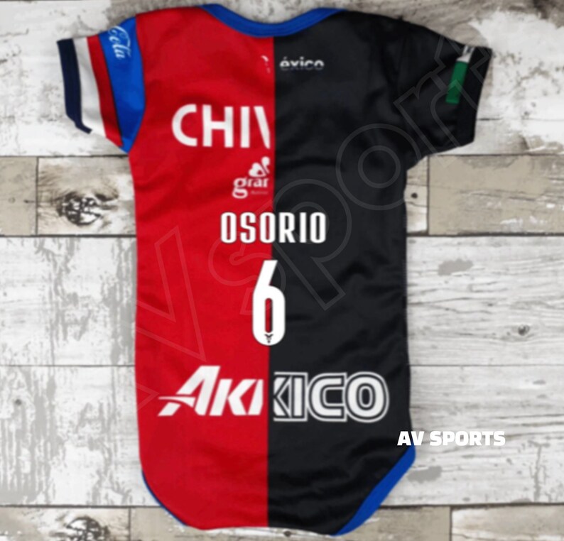 May include: A red and black soccer jersey with the text "CHIVAS" and "OSORIO 6" on the back. The jersey has a white logo on the front and the text "AKIKO" on the bottom.