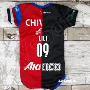 May include: A red and black soccer jersey with the text "CHIVAS" on the red side and "AKIKO" on the black side. The number "09" and the name "LILI" are printed on the back of the jersey.