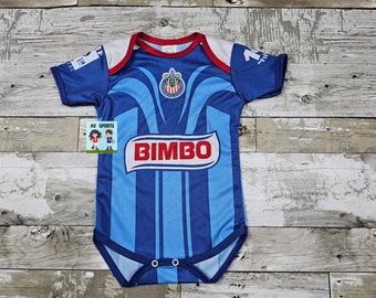 May include: A blue and white baby onesie with a soccer team logo and the word "BIMBO" printed on the front. The onesie has short sleeves and a snap closure.