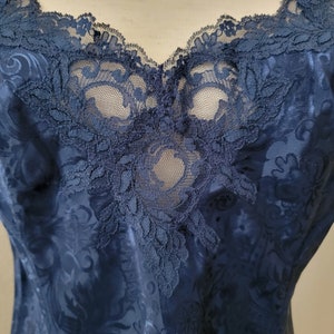 K&ouml;nnte beinhalten: Ein nachtblauer Satin-Schlafanzug mit einer Spitzenborte am Ausschnitt. Die Spitze ist ein zartes Blumenmuster.