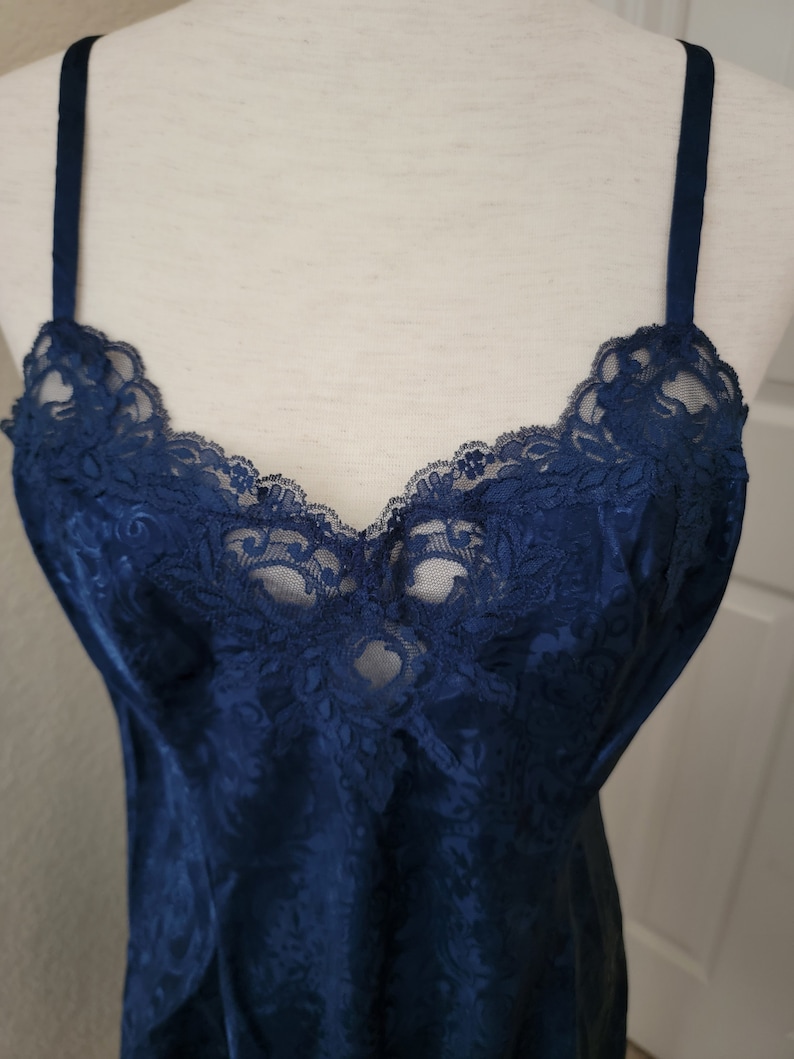 K&ouml;nnte beinhalten: Ein nachtblauer Satin-Schlafanzug mit einer Spitzenborte am Ausschnitt.