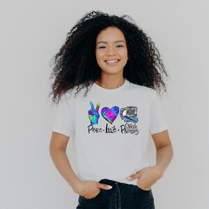 May include: A white t-shirt with a peace sign, heart, and a medical device. The text on the shirt reads "Peace Love Sterile Processing".