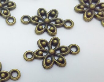 May include: Antique gold-toned metal flower charms with a loop on each side. The charms have a detailed design with a circle in the center and five petals.