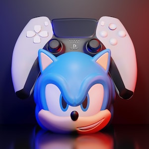May include: A blue and white Sonic the Hedgehog character figure with a PlayStation 5 controller in the background. The controller is white and black. The background is a gradient of red and blue.