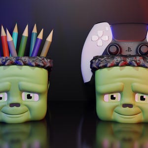 May include: Two green Frankenstein-themed pencil holders. One is filled with colored pencils and the other has a white and black video game controller on top.