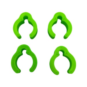 Puede incluir: Cuatro clips de plástico verde lima, cada uno con forma de 'C' redondeada con un pequeño agujero en la parte superior.