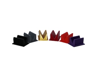 May include: Six card holders in different colors: black, gray, gold, red, and purple. Each holder is made of plastic and has a V-shaped opening to hold cards.