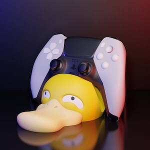 Op de afbeelding: Een gele eend met een witte snavel en zwarte ogen draagt een witte en zwarte videogamecontroller op zijn kop.