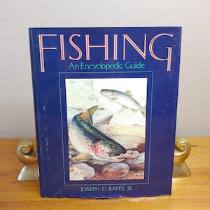 May include: A blue hardcover book titled "Fishing: An Encyclopedic Guide" by Joseph D. Bates, Jr. The cover features a watercolor illustration of two trout in a stream.