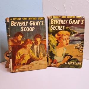 May include: Two vintage paperback books titled "Beverly Gray's Scoop" and "Beverly Gray's Secret." The covers feature illustrations of people in mid-century settings. The author's name, Clair Blank, is printed on both books.