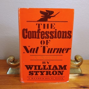 May include: A vintage paperback book with an orange cover featuring a black silhouette of an angel with a sword. The title is "The Confessions of Nat Turner" by William Styron. A Random House Book.
