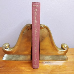 May include: A pair of gold metal bookends in the shape of a stylized bird with a book titled "Mathematical Tables and Formulas" by R.S. Burington standing between them.