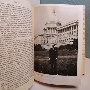 May include: A black and white photograph of Lyndon B. Johnson standing in front of the U.S. Capitol building. The image is from a book, with text visible on the left page. The caption reads "Congressional secretary Lyndon Johnson."
