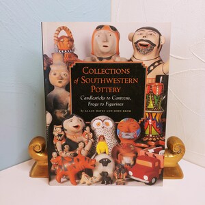May include: A hardcover book titled Collections of Southwestern Pottery: Candlesticks to Canteens, Frogs to Figurines by Allan Hayes and John Blom. The cover features a collage of colorful ceramic figurines, including an owl, a truck, and people.