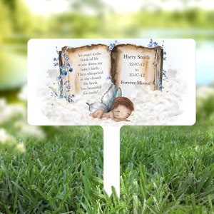 May include: A white memorial garden stake with a watercolor illustration of a book, a fairy, and clouds. The book has the text "An angel in the book of life wrote down my baby's birth. Then whispered as she closed the book 'too beautiful for earth'" and "Harry Smith 22-07-12 to 23-07-12 Forever Missed".